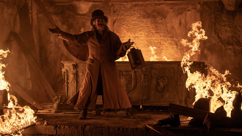 Willem Dafoe as Albin Eberhart von Franz cackling in front of a flaming coffin in Nosferatu (2024)