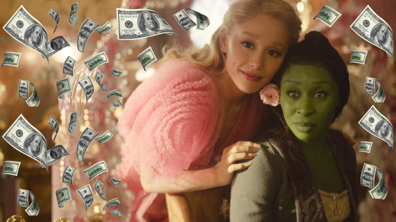 Cynthia Erivo's Elphaba and Ariana Grande's Glinda looking in the mirror surrounded by money in Wicked