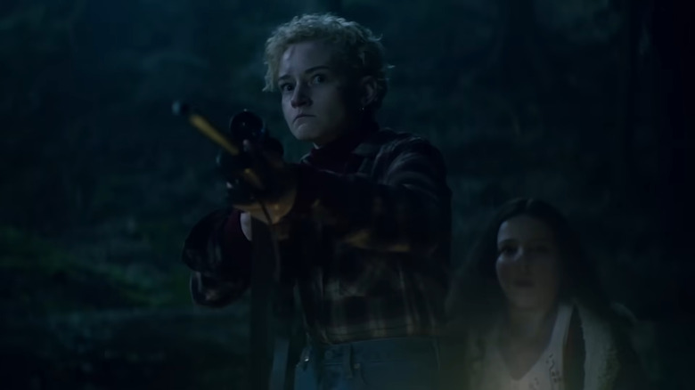 Julia Garner's Charlotte aiming a gun at the werewolf in Wolf Man