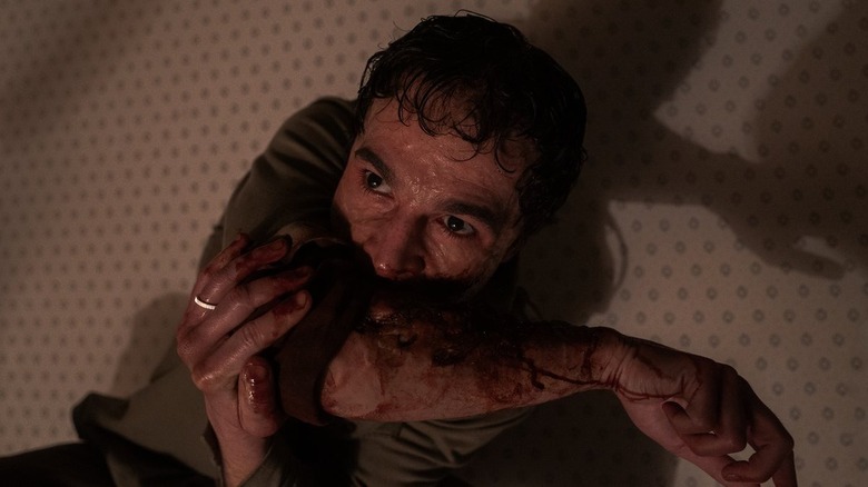 Christopher Abbott's Blake chewing on his own arm in Wolf Man (2025)