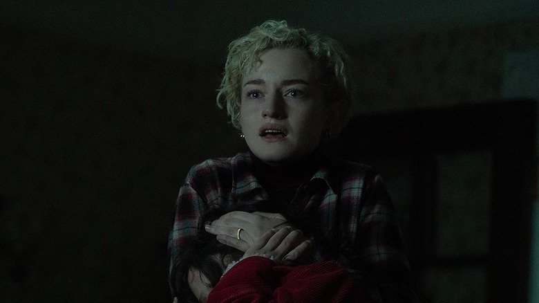 Julia Garner's Charlotte holding her daughter as they look at Blake in horror in Wolf Man