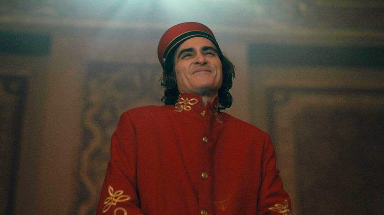 Joaquin Phoenix como Arthur Fleck em pé no teatro como um levante no Coringa