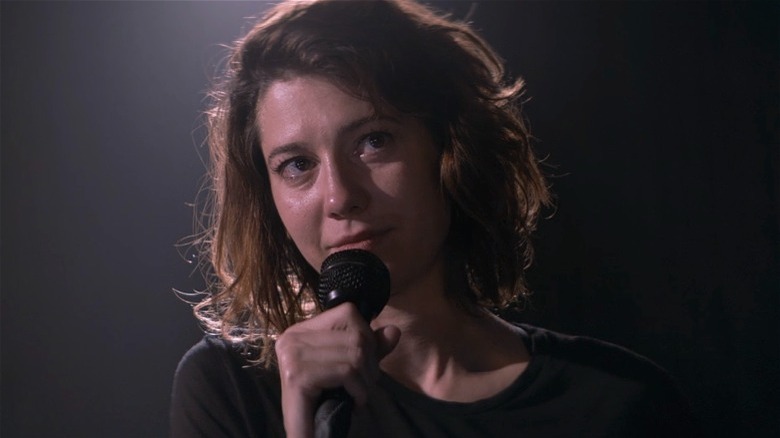 Mary Elizabeth Winstead as Nina holding microphone with tear in eye