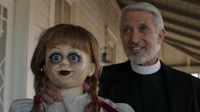 A priest holds up the haunted Annabelle doll