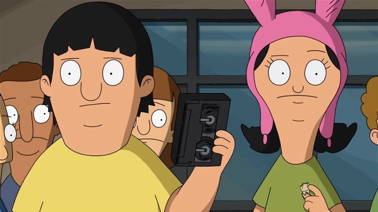 Gene holds up VHS tape next to Louise in pink hat