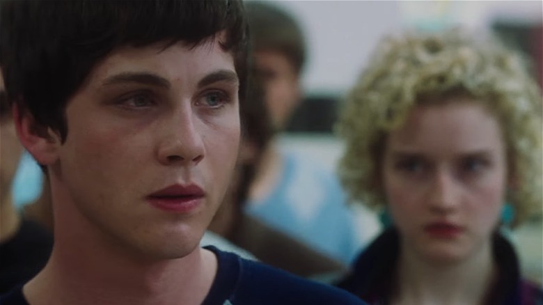 Closeup of Logan Lerman with fuzzy Julia Garner visible behind him