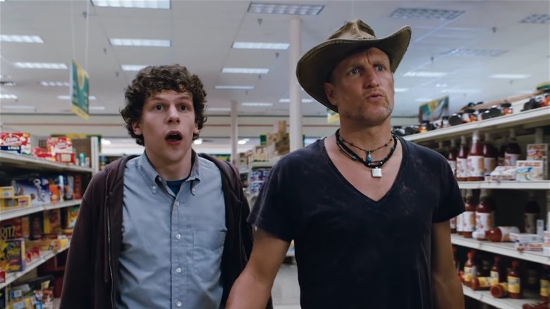 Jesse Eisenberg and Woody Harrelson in cowboy hat walking supermarket