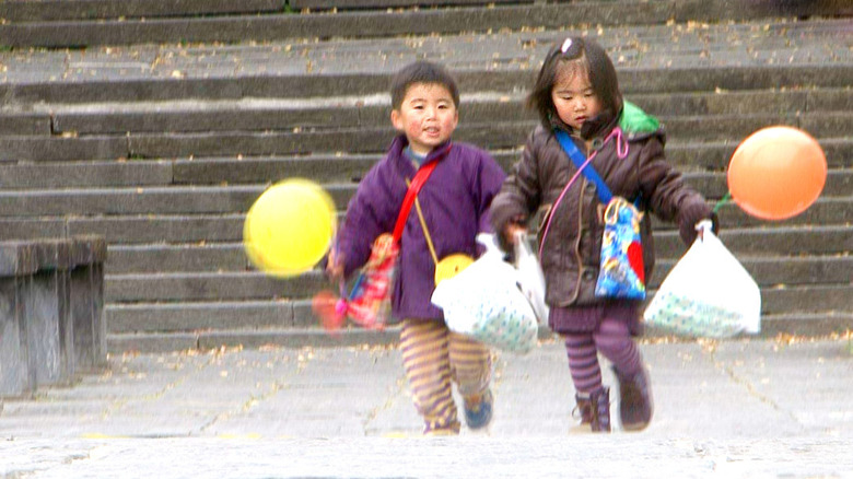 Two children carry their purchases and balloons. 