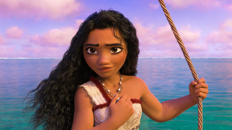 Moana in Moana 2 holding her necklace against her heart while holding a rope on the water