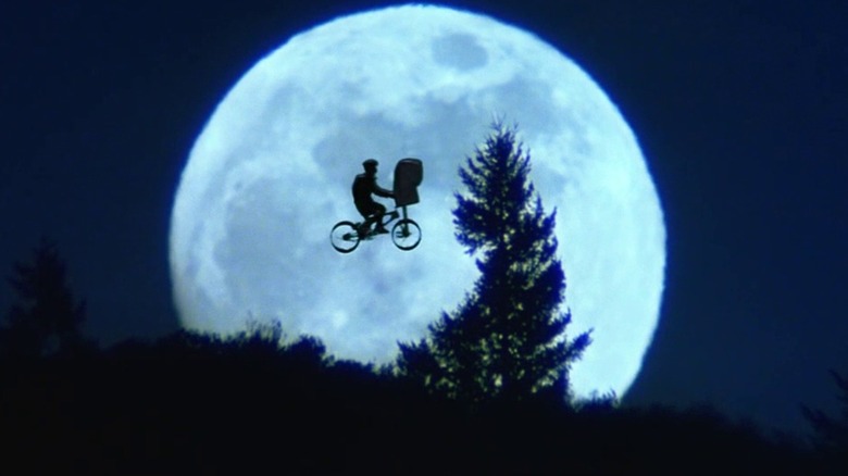 Boy and alien on bike soar before moon