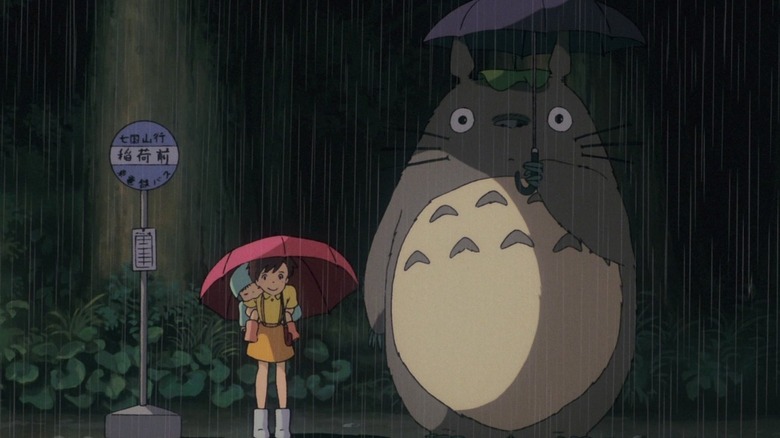 Girl stands in rain next to Totoro