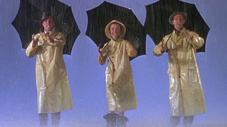 Three people dance in rain