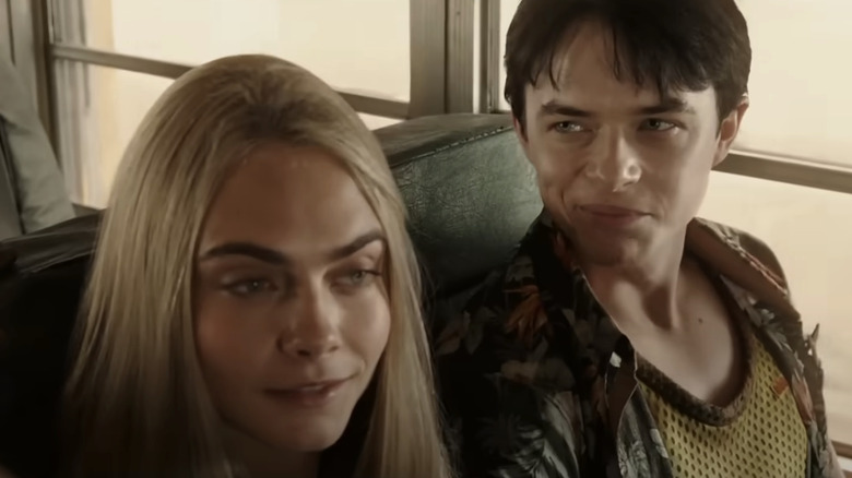 Valerian dari Dane DeHaan dan Laureline dari Cara Delevingne duduk berdampingan di dalam bus di Valerian dan Kota Seribu Planet