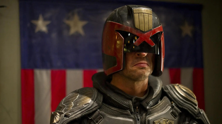 Karl Urban as Judge Dredd standing in front of the flag in Dredd