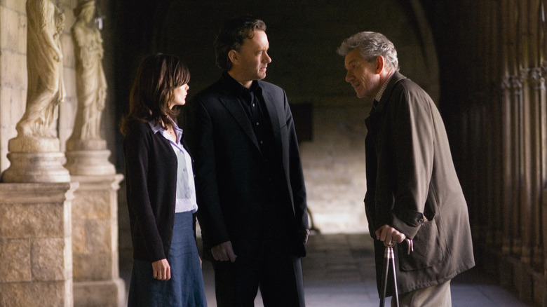 Robert Langdon and Sophie Neveu talk to Teabing in a dark hallway