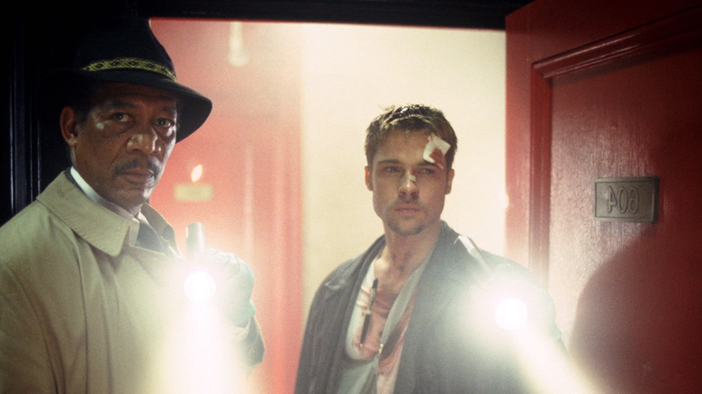 Morgan Freeman as Somerset and Brad Pitt as Mills entering an apartment holding flashlights in Seven