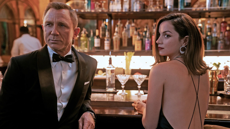 a man in a suit with a woman in a dress sitting at a bar