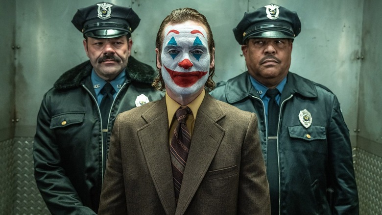 Arthur Fleck being escorted by police officers in Joker: Folie a Deux