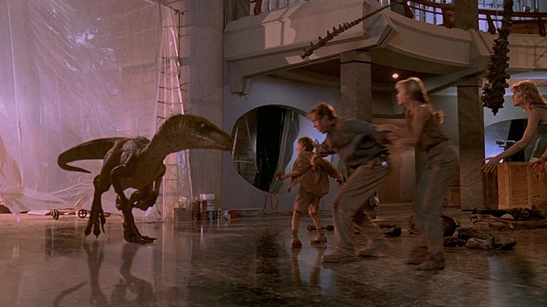 A Raptor approaches Sam Neil's doctor Alan Grant, Laura Dern's Ellie Sattler, Joseph Mazzello's Tim Murphy, and Ariana Richards' Lex Murphy in the visitor center in Jurassic Park