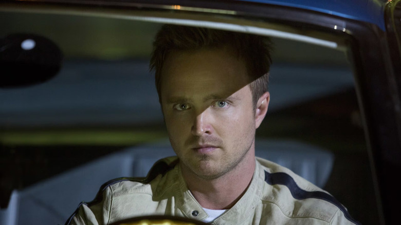 Tobey Ma﻿rshall (Aa﻿ron Paul) sits in a ca﻿r at night and looks out the windshield in Need for Speed