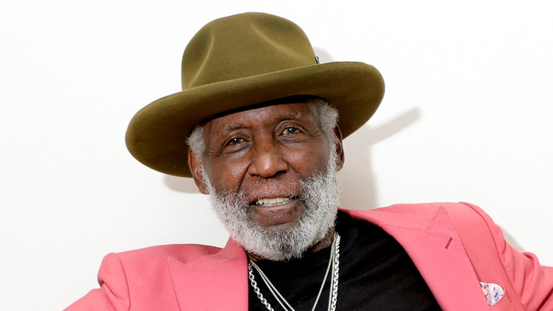 Richard Roundtree wearing a green hat and pink jacket