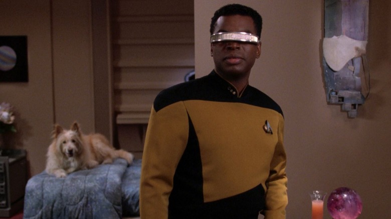 Geordi in Aquiel's room, a dog is on the bed behind him. From Star Trek: The Next Generation