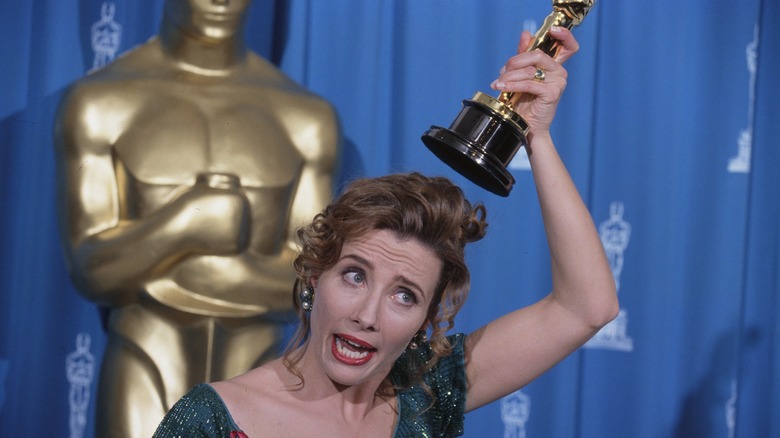 Emma Thompson making a goofy face and holding her Oscar above her head