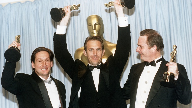 Kevin Costner holding two Oscars over his head, with the producers of Dances with Wolves