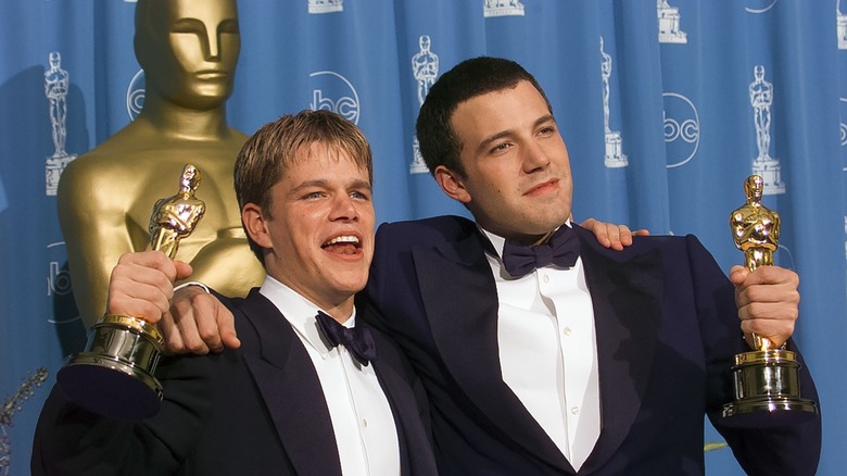 Matt Damon and Ben Affleck, holding their Oscars up