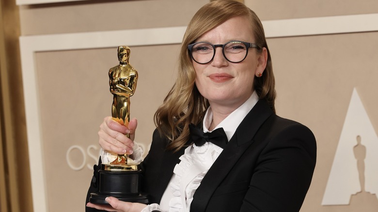 Sarah Polley holding up her Oscar, supporting it by the base