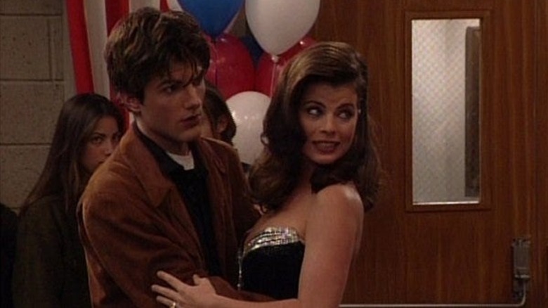 Griff Hawkins holds a sparkly-dressed Yasmine Bleeth as they both look off to the right, seemingly interrupted, in Boy Meets World