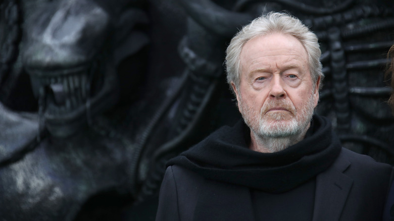 Ridley Scott standing in front of Alien mural