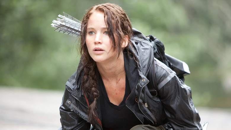 Jennifer Lawrence as Katniss Everdeen kneeling down with her quill on her back in The Hunger Games