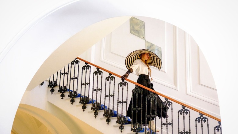 Blake Lively's Emily walking down the stairs in her big hat in Another Simple Favor