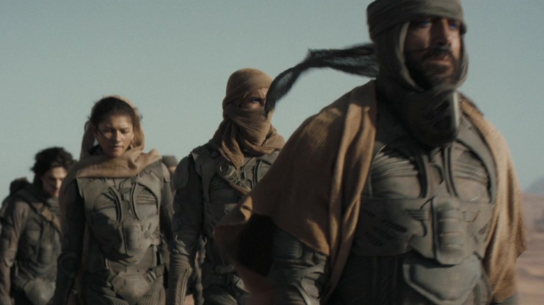 Zendaya's Chani and Javier Bardem's Stilgar march in a line of Fremen in Dune