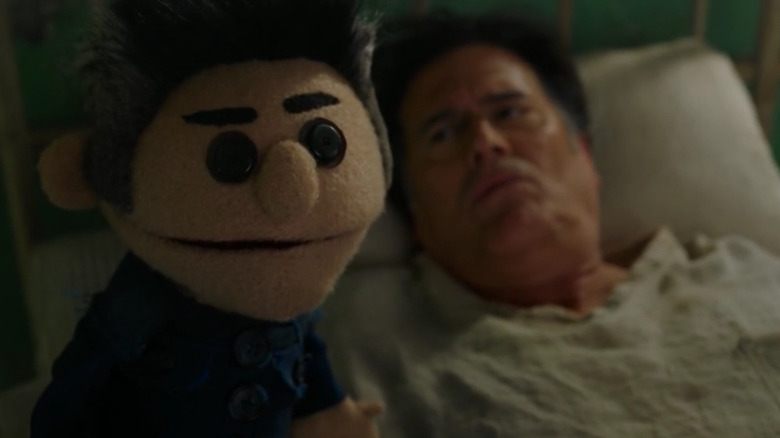 Ash lies in bed with a lookalike puppet next to him