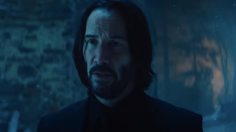 John Wick stands bathed in blue light in Ballerina