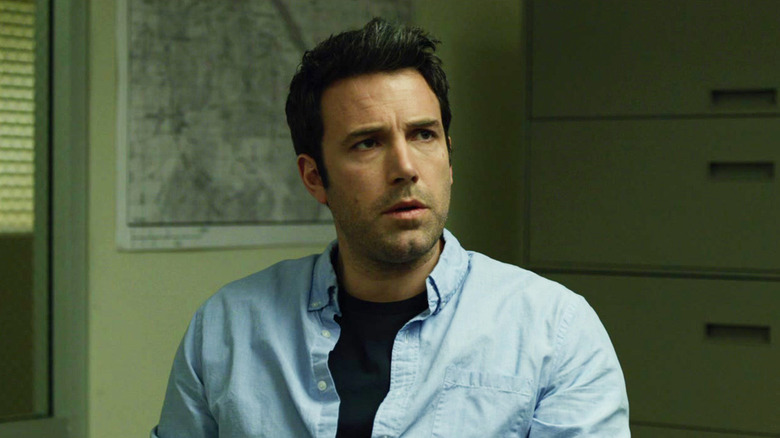 Nick Dunne sits looking concerned in an office environment in Gone Girl