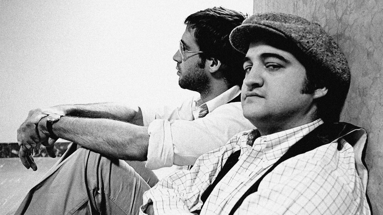 John Belushi and Chevy Chase sit in a hallway behind the scenes of SNL