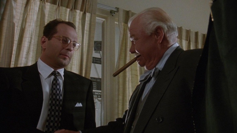 Bruce Willis as Peter Fallow shaking hands with a guy smoking a cigar in The Bonfire of the Vanities