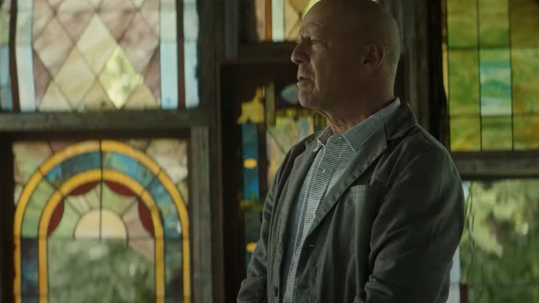 Bruce Willis as Valmora standing in front of stained glass in Assassin