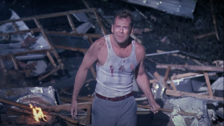 Bruce Willis' John McClane stands amid the wreckage of his trailer home in Loaded Weapon