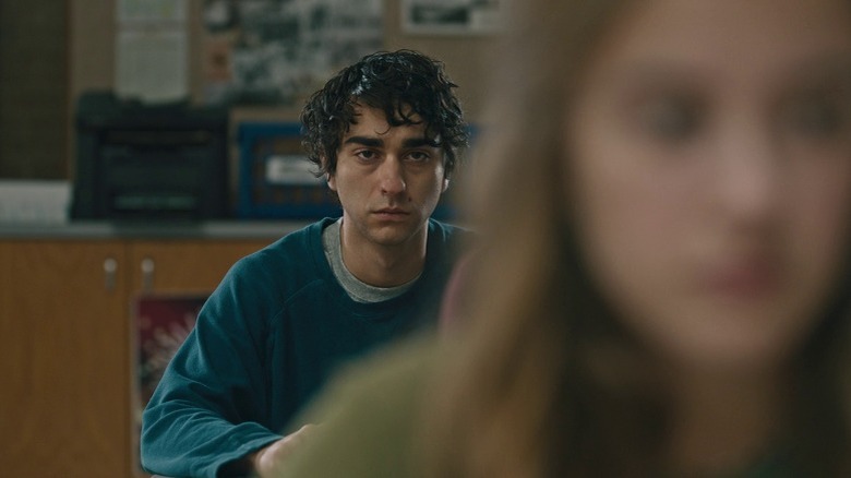 Peter Graham sitting behind a girl in class with a despondent expression in Hereditary