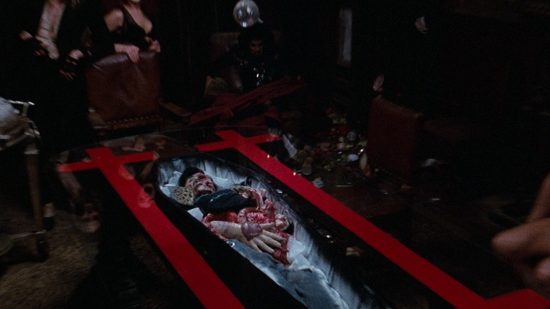 Dinner guests jump in shock away from Eddie's body under the table in The Rocky Horror Picture Show