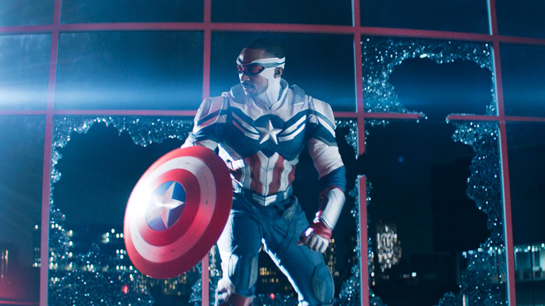 Sam Wilson dressed like Captain America in front of a broken window