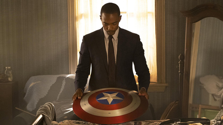 Falcon and Winter Soldier: Sam Wilson holds Captain America Shield in a business suit