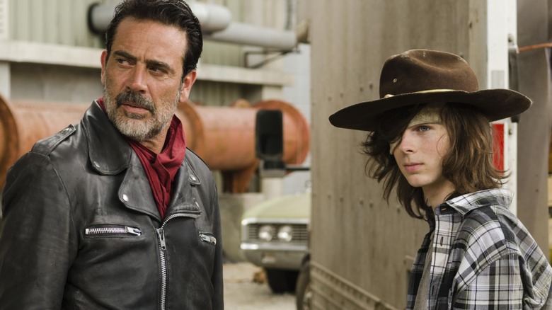 Jeffrey Dean Morgan's Negan and Chandler Riggs' Carl look seriously at something off screen in The Walking Dead