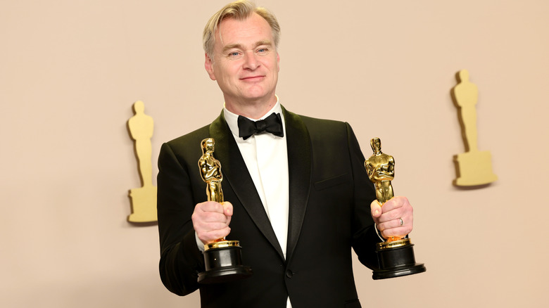 Christopher Nolan holding two Oscar statutes