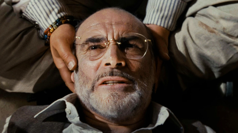 Sean Connery's Henry Jones Sr lays on the floor while someone cradles his head in Indiana Jones and the Last Crusade