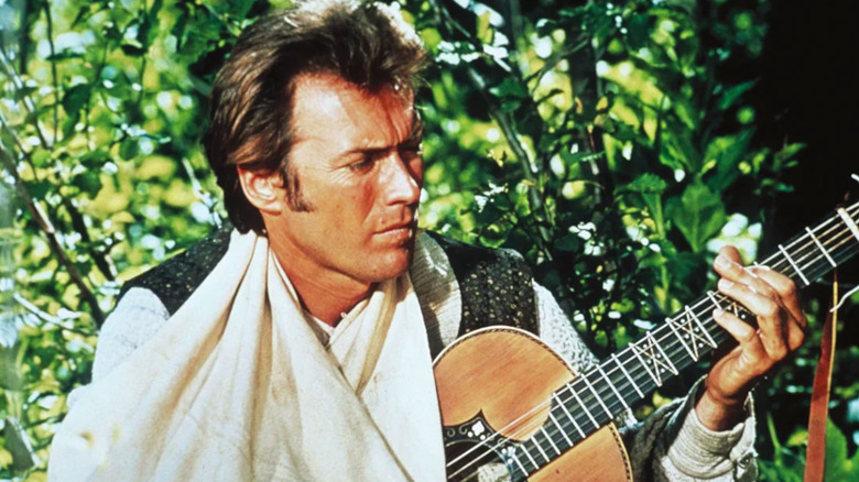 Clint Eastwood strums a guitar with his arm in a sling as Pardner in Paint Your Wagon